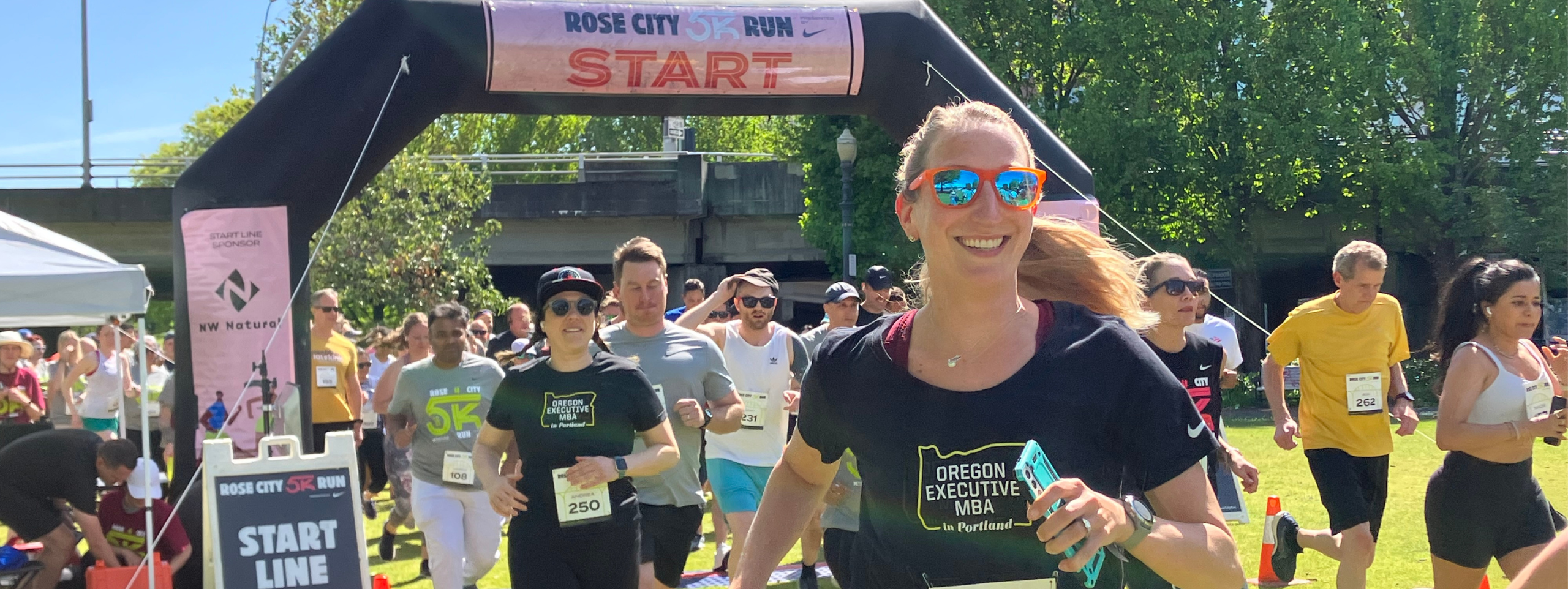 Smiling lady runner leads the race for the Rose City 5K with pink sunglasses