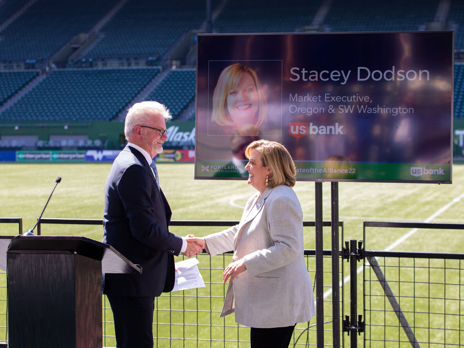 John Maher of the Oregonian and Stacey Dodson of U.S. Bank shake hands next to a podium